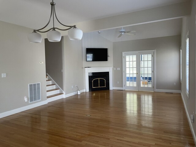 unfurnished living room featuring a fireplace, lofted ceiling, wood finished floors, and visible vents