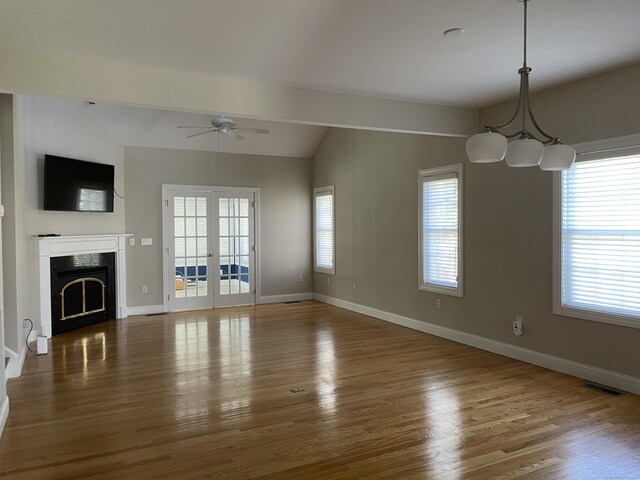 unfurnished living room with visible vents, lofted ceiling, wood finished floors, and ceiling fan with notable chandelier