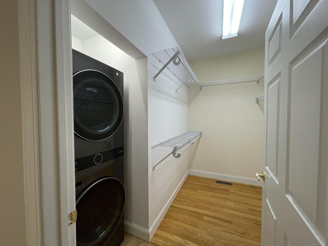 spacious closet with light wood-type flooring and stacked washer / drying machine