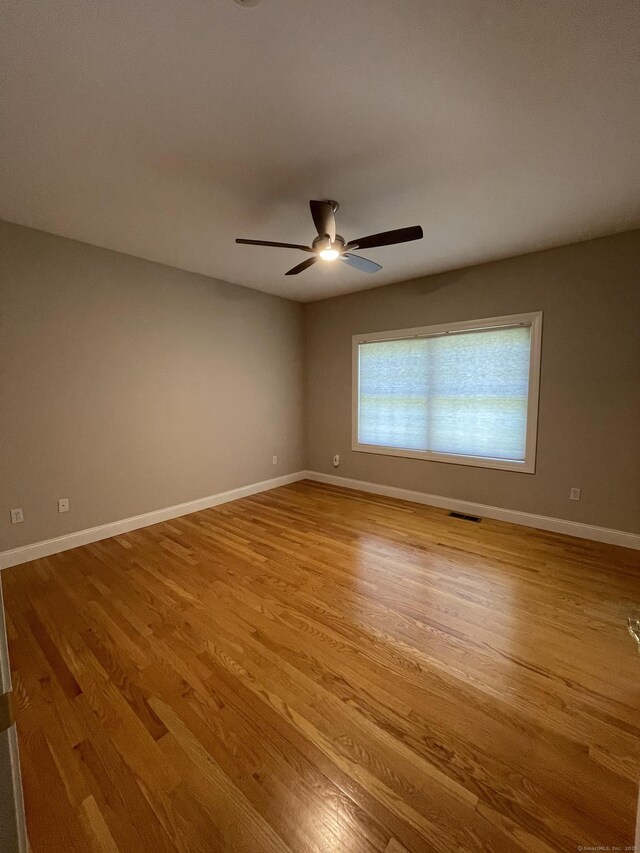 unfurnished room featuring baseboards, light wood finished floors, ceiling fan, and visible vents