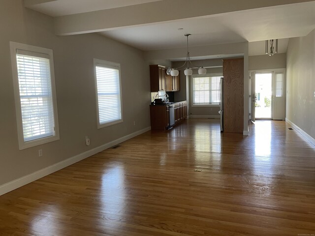 unfurnished dining area featuring baseboards, dark wood-style floors, and a notable chandelier