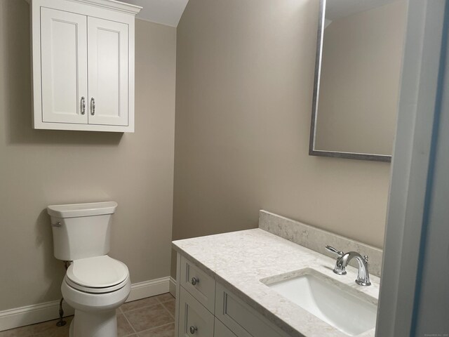 half bathroom featuring toilet, baseboards, tile patterned floors, and vanity