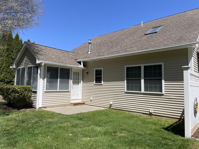 back of property featuring a lawn and a shingled roof