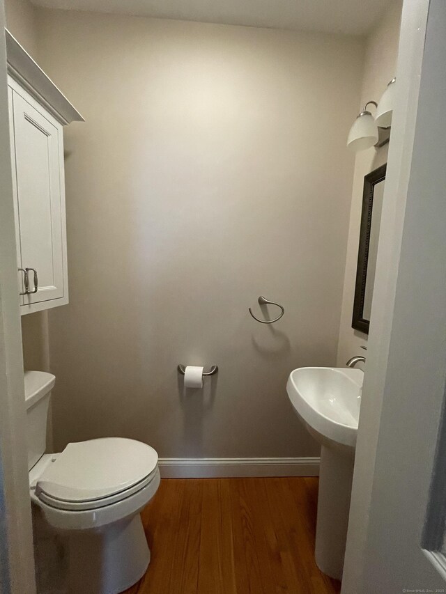 bathroom with baseboards, a sink, wood finished floors, and toilet