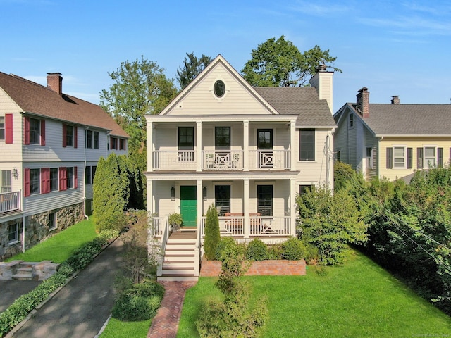 neoclassical home with a porch, stairs, a front lawn, and a balcony