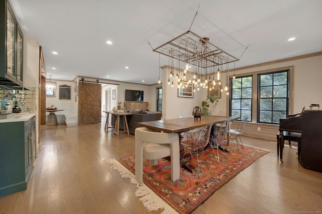 dining room with crown molding, recessed lighting, a barn door, and light wood finished floors