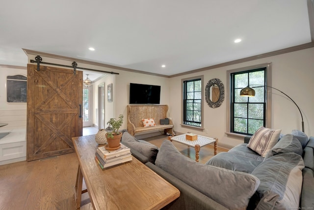 living room with crown molding, light wood-style floors, recessed lighting, and a barn door