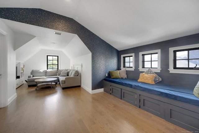 living area featuring visible vents, wood finished floors, vaulted ceiling, and wallpapered walls