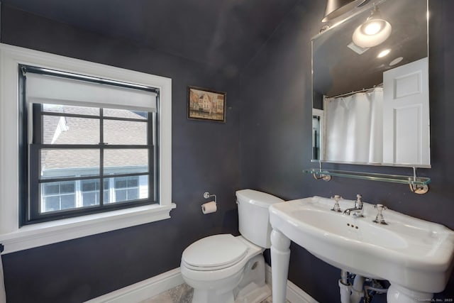bathroom featuring a healthy amount of sunlight, baseboards, toilet, and a sink