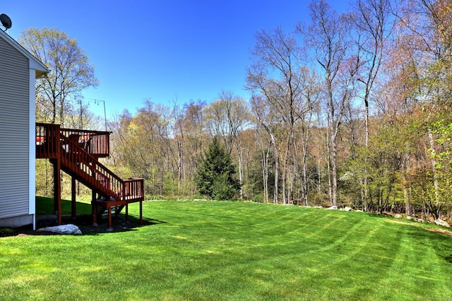 view of yard with a deck, stairway, and a forest view
