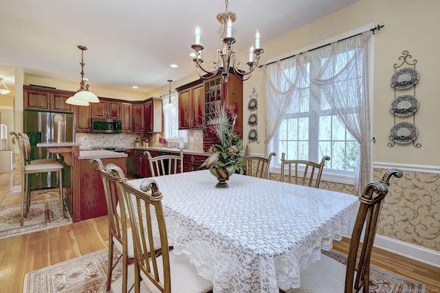 dining area with light wood-style floors and a chandelier