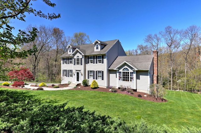 colonial home with a chimney and a front yard