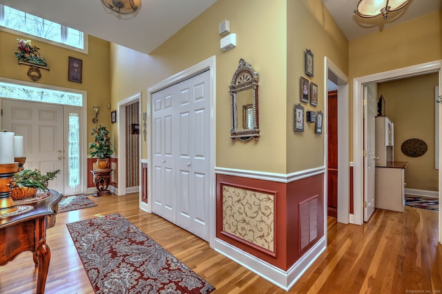 foyer with visible vents, baseboards, a high ceiling, and light wood-style floors
