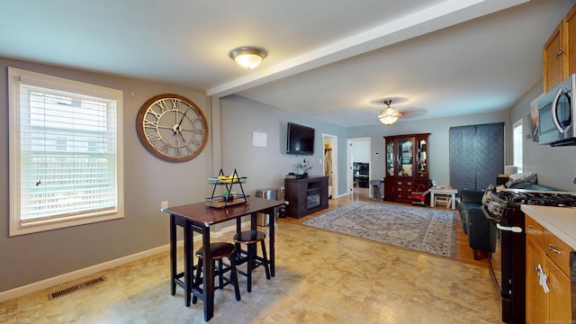 dining room featuring baseboards, light flooring, and a ceiling fan