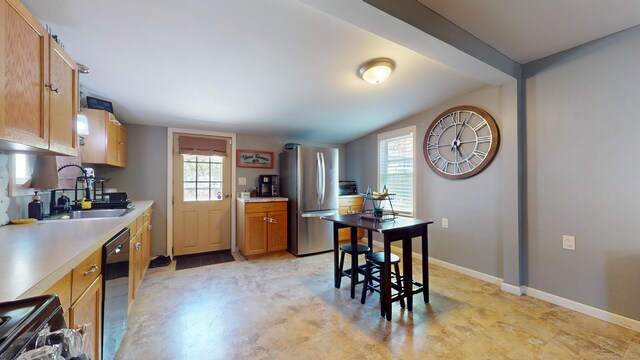kitchen with freestanding refrigerator, a sink, stove, and light countertops