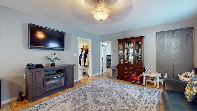 living area with baseboards, wood finished floors, and a ceiling fan