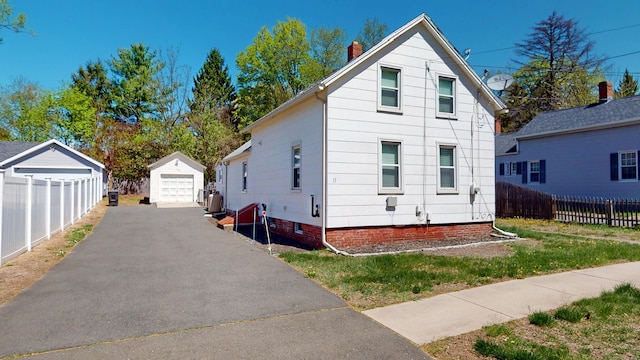 view of front of property with fence, a garage, an outdoor structure, driveway, and a chimney