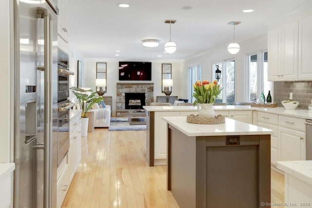 81 Silver Hill Rd, Ridgefield, CT 06877 - kitchen featuring white cabinets, hanging light fixtures, light wood finished floors, a fireplace, and open floor plan