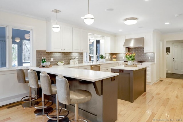 81 Silver Hill Rd, Ridgefield, CT 06877 - kitchen with light wood-style floors, white cabinetry, a peninsula, and wall chimney range hood