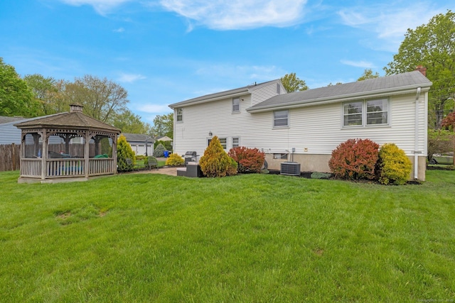rear view of house with a gazebo, a yard, central air condition unit, and a chimney