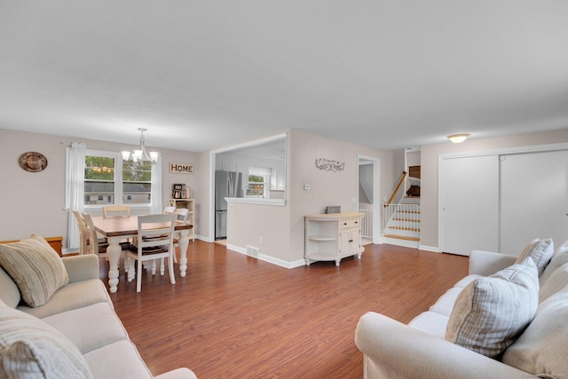 living room featuring a chandelier, stairway, dark wood-style flooring, and baseboards