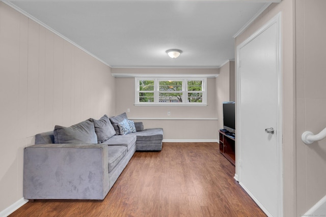 living area with ornamental molding, wood finished floors, and baseboards