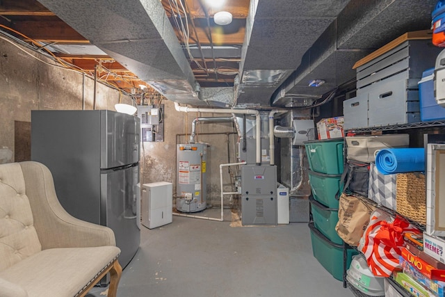 unfinished below grade area featuring water heater, freestanding refrigerator, and heating unit