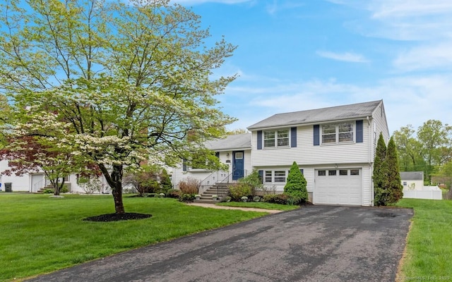 tri-level home with asphalt driveway, a front yard, and an attached garage