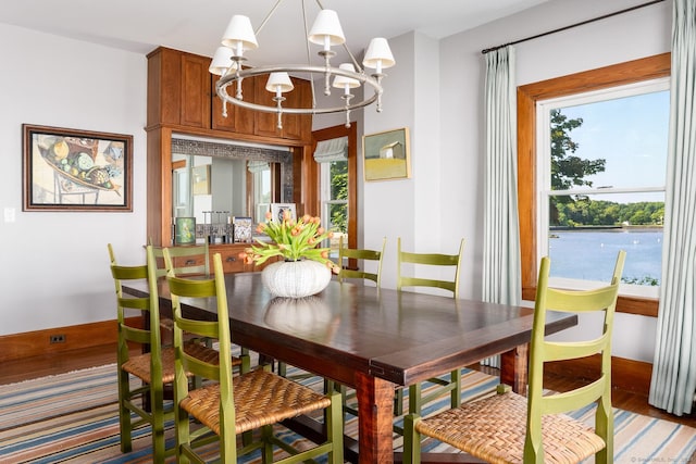 dining space with baseboards, wood finished floors, and a notable chandelier