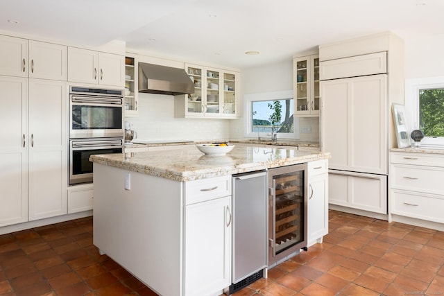 kitchen with extractor fan, wine cooler, a healthy amount of sunlight, and double oven