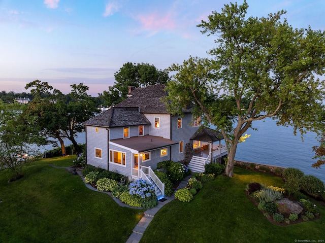 view of front of home featuring a front lawn, a chimney, stairs, a gazebo, and a water view