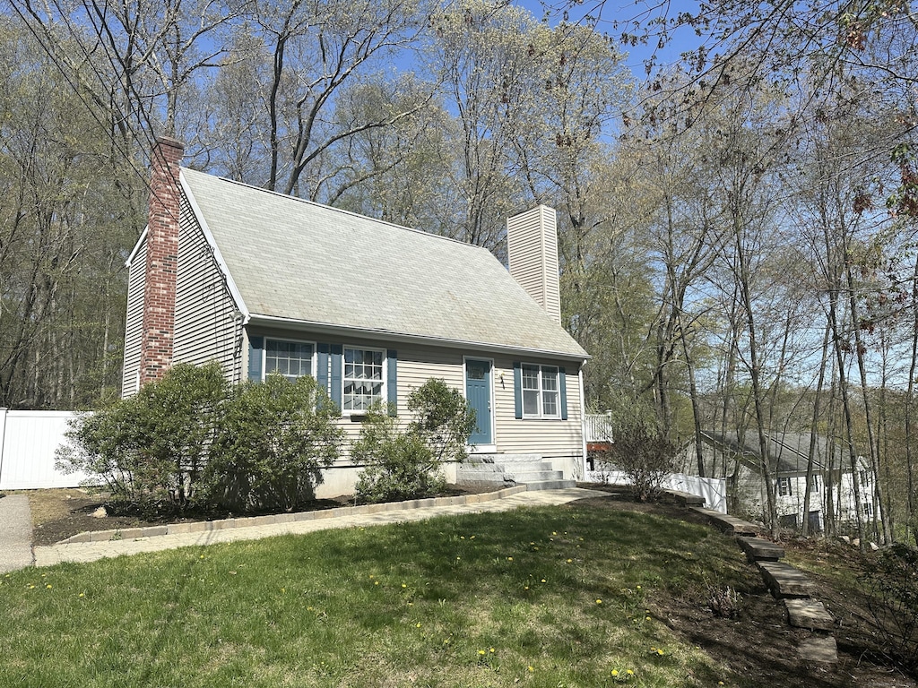 view of front of home with fence, a chimney, and a front lawn