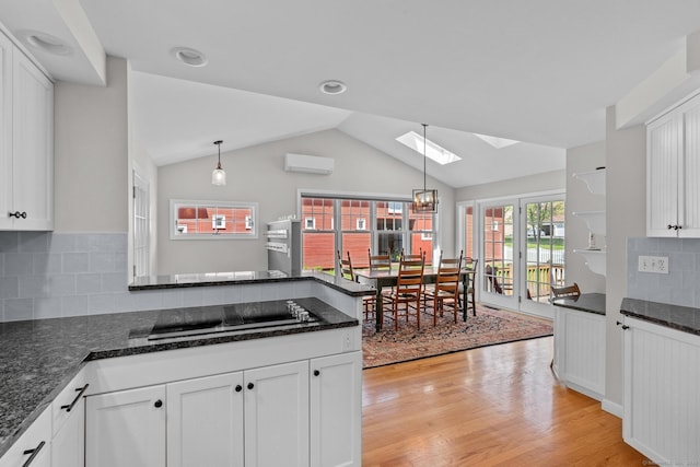 309 N Grand St, Suffield, CT 06093 - kitchen featuring a skylight, a wall mounted air conditioner, white cabinets, black electric cooktop, and vaulted ceiling