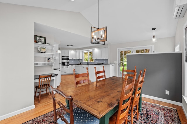 309 N Grand St, Suffield, CT 06093 - dining area with an AC wall unit, light wood-type flooring, a chandelier, lofted ceiling, and baseboards