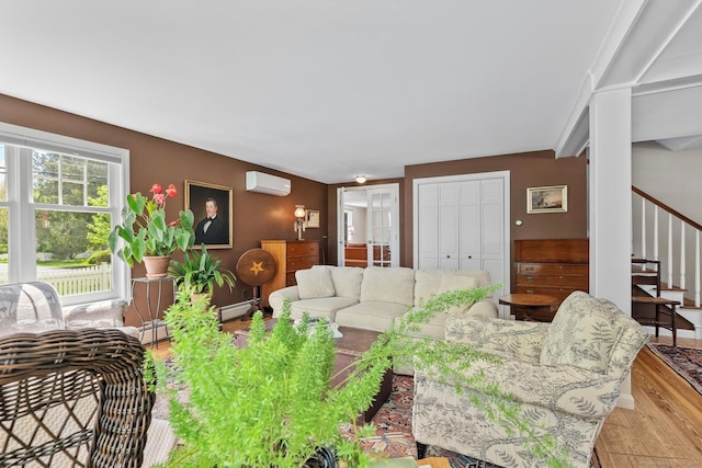 309 N Grand St, Suffield, CT 06093 - living area with a wall unit AC, wood finished floors, stairs, baseboard heating, and baseboards