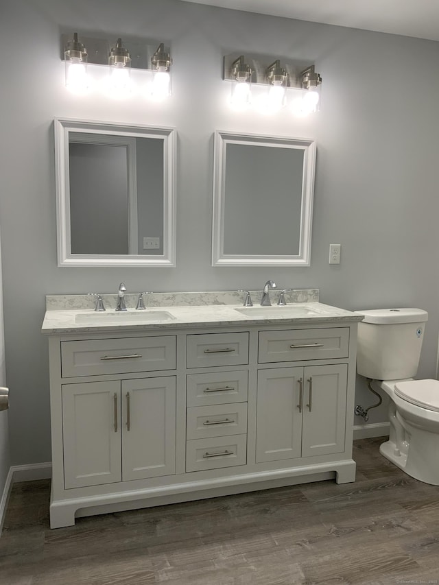 full bathroom with a sink, baseboards, toilet, and wood finished floors