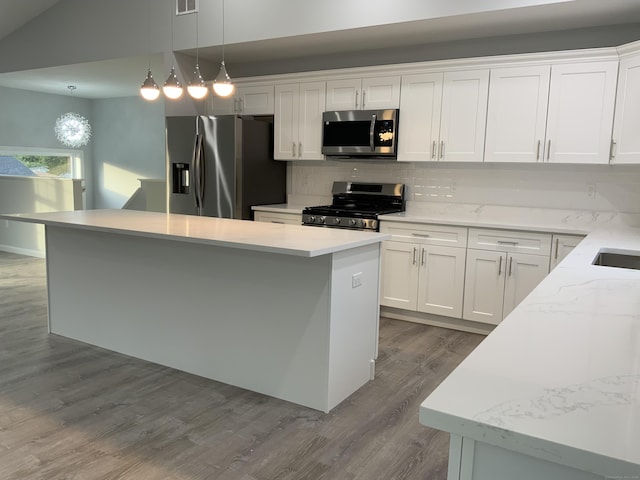 kitchen with decorative backsplash, a kitchen island, white cabinetry, dark wood finished floors, and appliances with stainless steel finishes