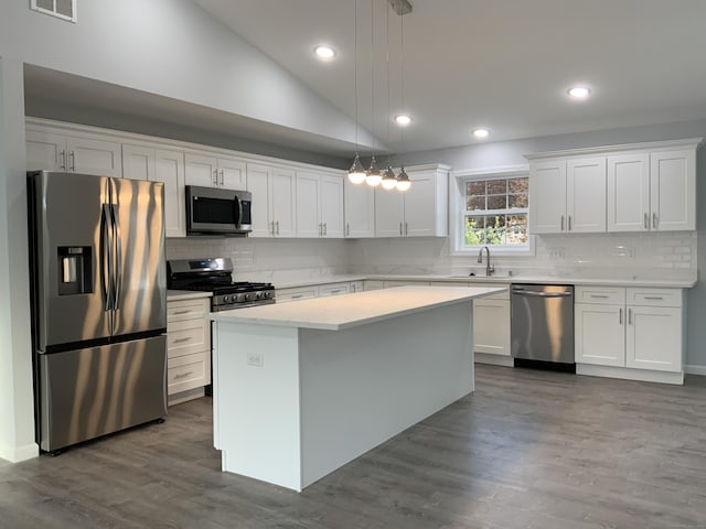 kitchen with white cabinets, appliances with stainless steel finishes, decorative backsplash, and a center island