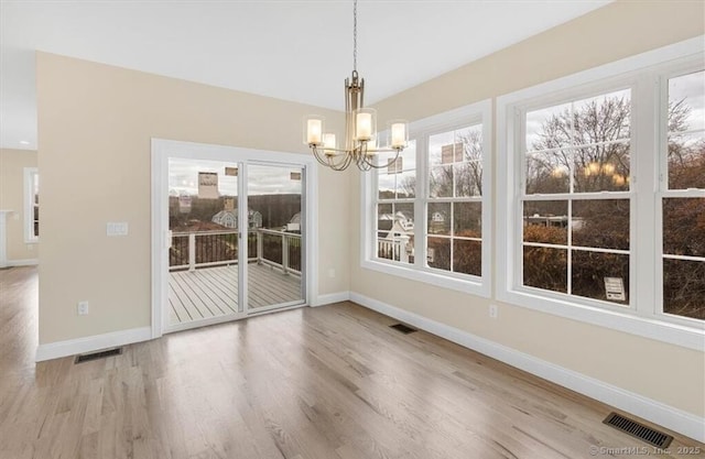 unfurnished dining area with visible vents, wood finished floors, and a chandelier