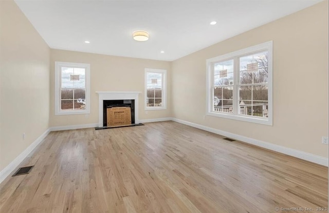 unfurnished living room with baseboards, light wood-type flooring, and visible vents