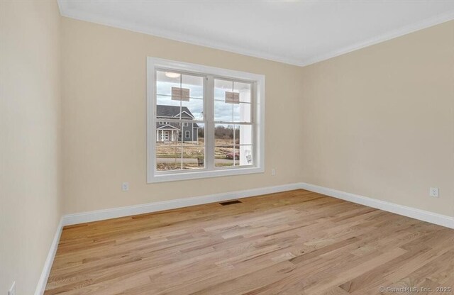 unfurnished room with baseboards, visible vents, ornamental molding, and light wood-style floors