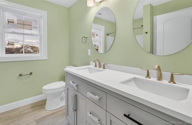 full bath with toilet, baseboards, a sink, and wood finished floors