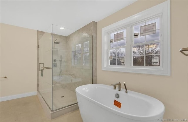 bathroom featuring baseboards, a stall shower, a freestanding bath, and recessed lighting