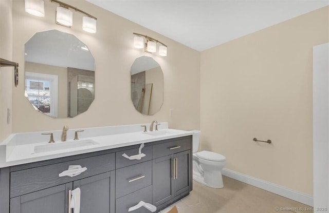 bathroom with double vanity, a sink, baseboards, and toilet