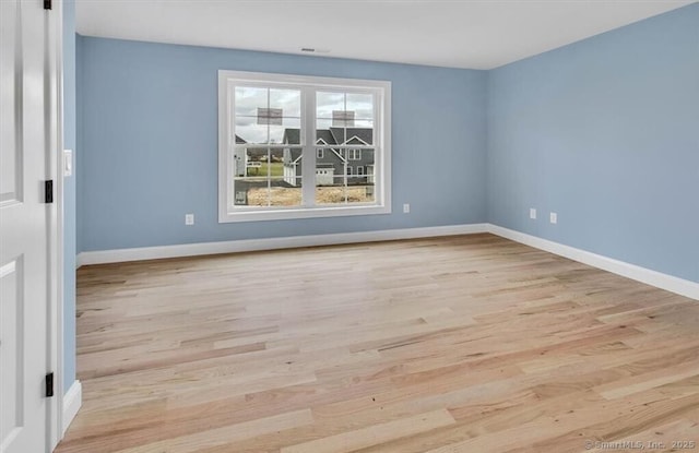 empty room featuring baseboards and light wood finished floors