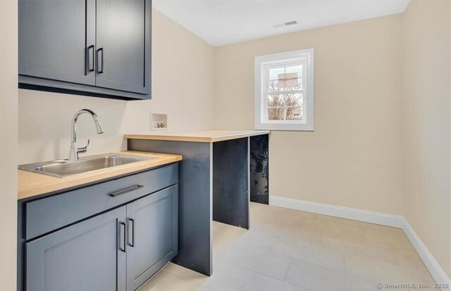 washroom with a sink, baseboards, cabinet space, and hookup for a washing machine