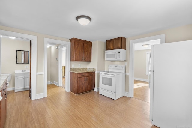 kitchen with white appliances, baseboards, light wood-style flooring, and light countertops