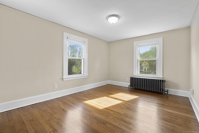 unfurnished room with baseboards, plenty of natural light, wood finished floors, and radiator