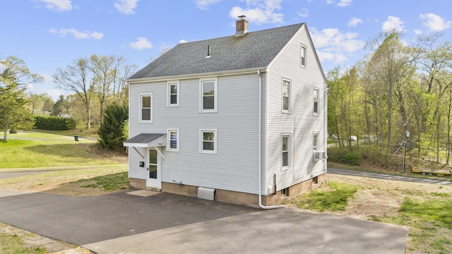exterior space featuring roof with shingles and a chimney