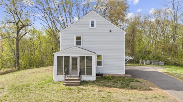 back of property with a yard, a sunroom, and driveway